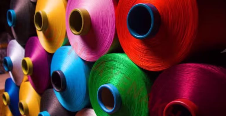 نمای نزدیک از نخ‌ها و الیاف پلی‌استر در کارخانه نساجی