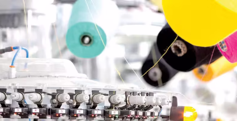 کارگران مشغول به کار با ماشین‌آلات قدیمی در کارخانه‌ای نساجی در ایران